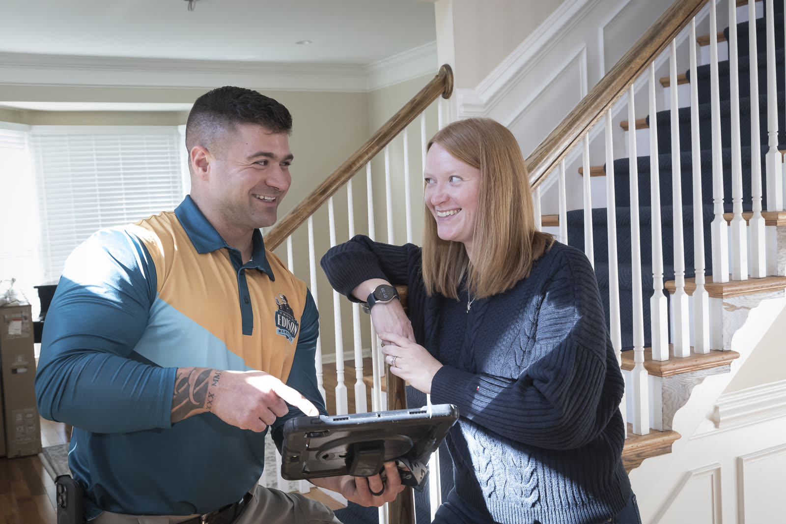 A Thomas Edison electrician walking a happy homeowner through the work on a tablet